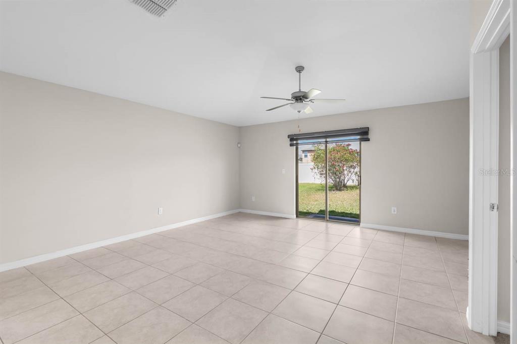An empty room with light-colored tile flooring, a ceiling fan, and sliding glass doors — 6823 KING CREEK DRIVE, SUN CITY CENTER, FL