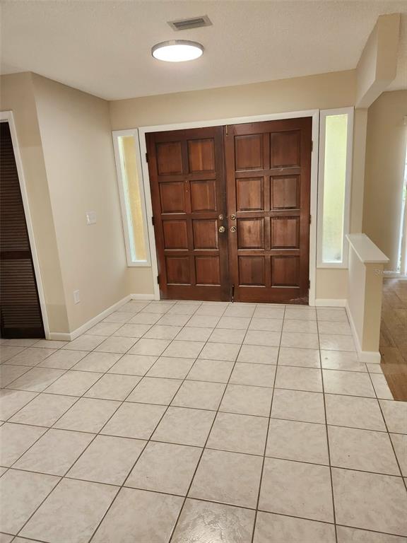 An entryway features light-colored tile flooring, beige walls, and double wood doors with sidelights — 3215 LAKE SAXON DRIVE, LAND O LAKES, FL