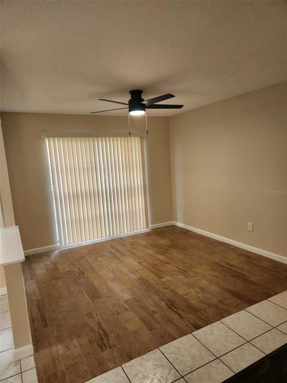 A room with wood-look tile flooring, a ceiling fan, and vertical blinds over a sliding door — 3215 LAKE SAXON DRIVE, LAND O LAKES, FL