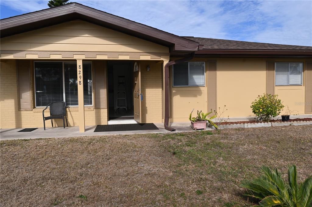A single-story house with a tan brick facade, brown trim, and a covered front porch — 8298 FAY AVENUE, NORTH PORT, FL