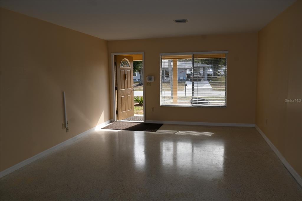 An empty room with light-colored walls, a polished concrete floor, a front door, and windows — 8298 FAY AVENUE, NORTH PORT, FL