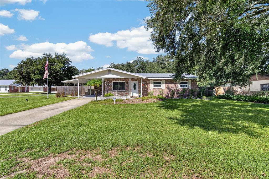 A single-story brick house features a front carport, a covered porch, and a large lawn — 2801 BLAIN ACRES ROAD, PLANT CITY, FL