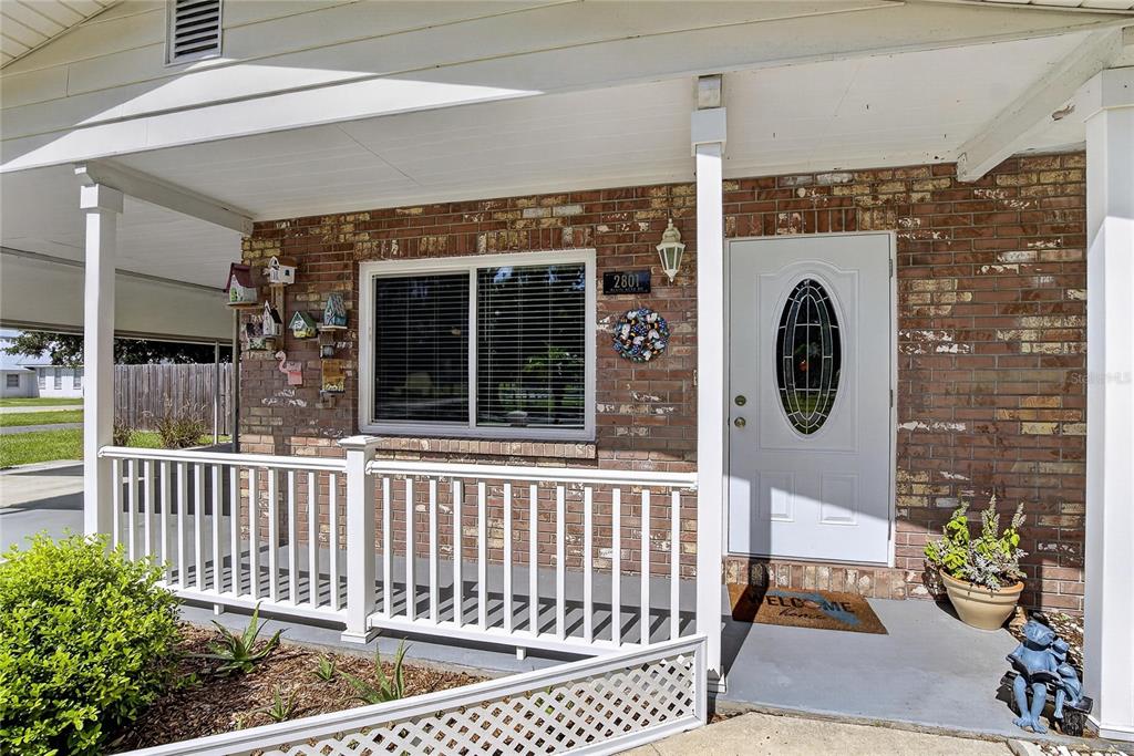 A brick house exterior features a white front door, a porch with railing, and birdhouses — 2801 BLAIN ACRES ROAD, PLANT CITY, FL