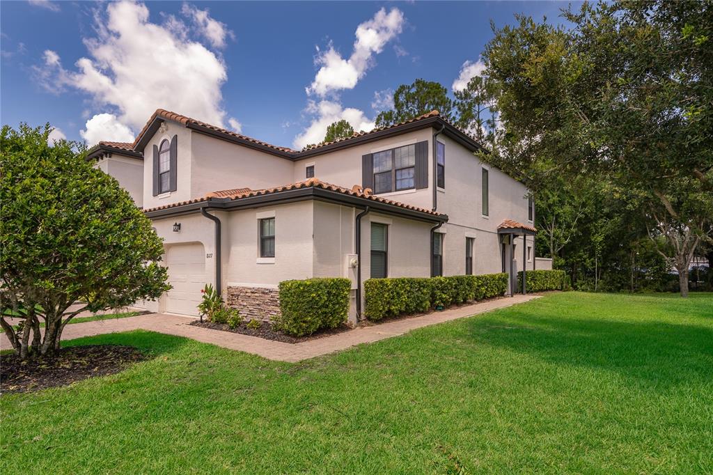 A two-story stucco townhouse with a tile roof, a garage, and a landscaped side yard — 8127 ROSEVILLE BOULEVARD, DAVENPORT, FL