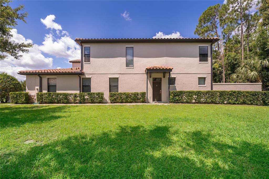 A two-story beige house with a tiled roof and a small front lawn — 8127 ROSEVILLE BOULEVARD, DAVENPORT, FL