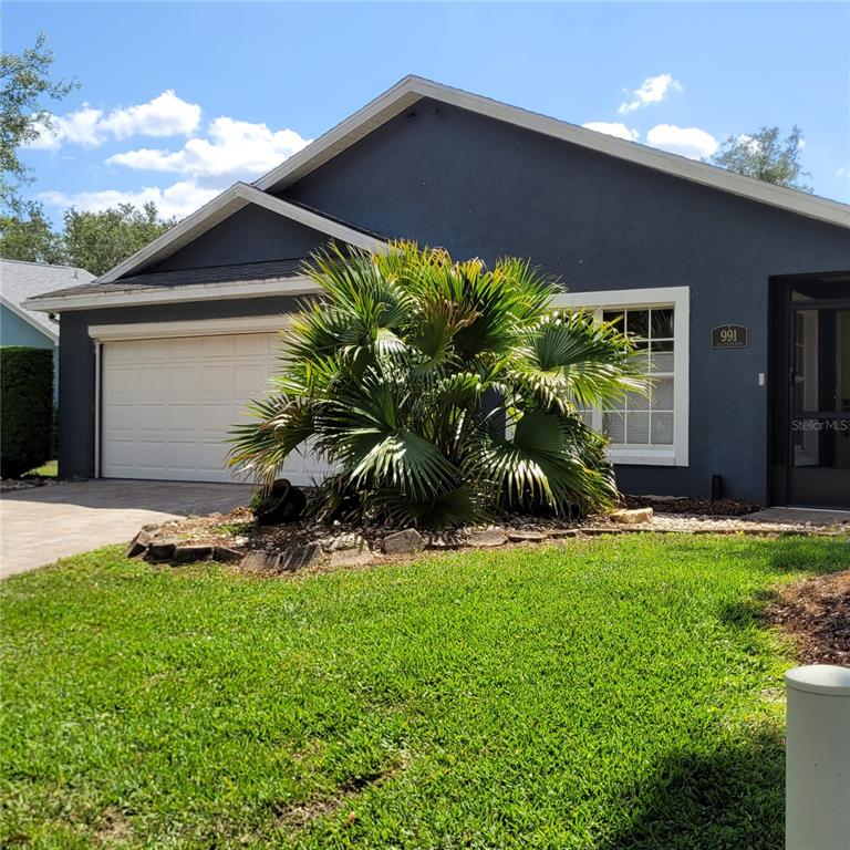 A dark gray house exterior features a two-car garage, a large palm tree, and landscaping — 991 OLD CUTLER ROAD, LAKE WALES, FL