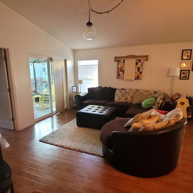 A living room features wood flooring, a sectional sofa, an ottoman, and a sliding glass door — 991 OLD CUTLER ROAD, LAKE WALES, FL