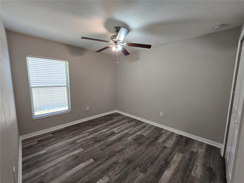 An empty bedroom with grey walls, wood-look flooring, a ceiling fan, and a window — 838 OLIVE CONCH STREET, RUSKIN, FL