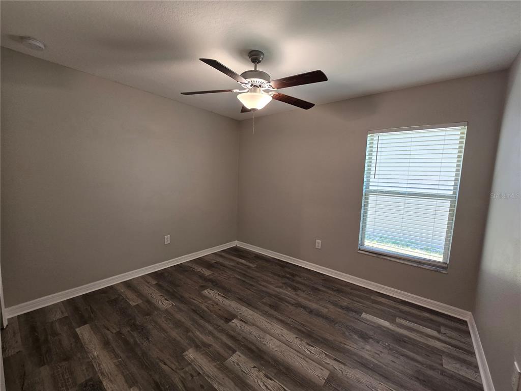 An empty bedroom features gray walls, wood-look flooring, a ceiling fan, and a window — 838 OLIVE CONCH STREET, RUSKIN, FL