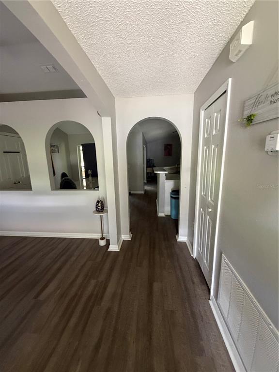 A hallway with arched doorways, wood-look flooring, and a white closet door — 346 COCOA COURT, KISSIMMEE, FL