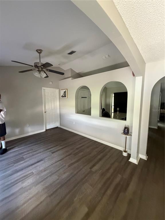 A living room features wood-look flooring, a vaulted ceiling with a fan, and arched cutouts — 346 COCOA COURT, KISSIMMEE, FL