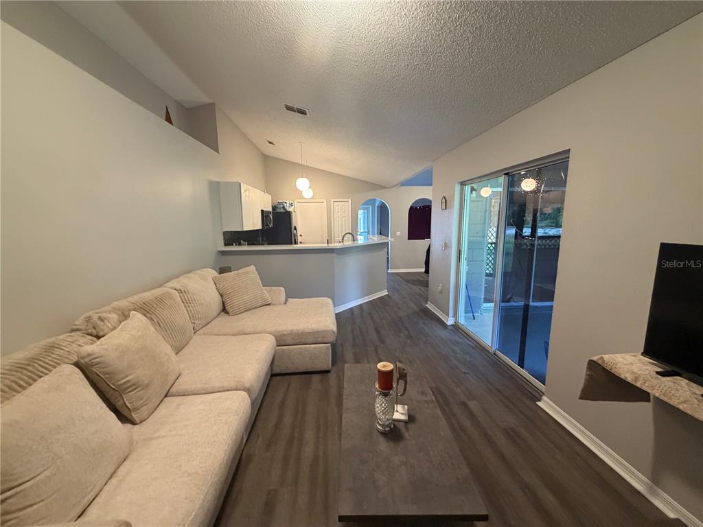 A living room with a sectional sofa, coffee table, and sliding glass doors to a patio — 346 COCOA COURT, KISSIMMEE, FL