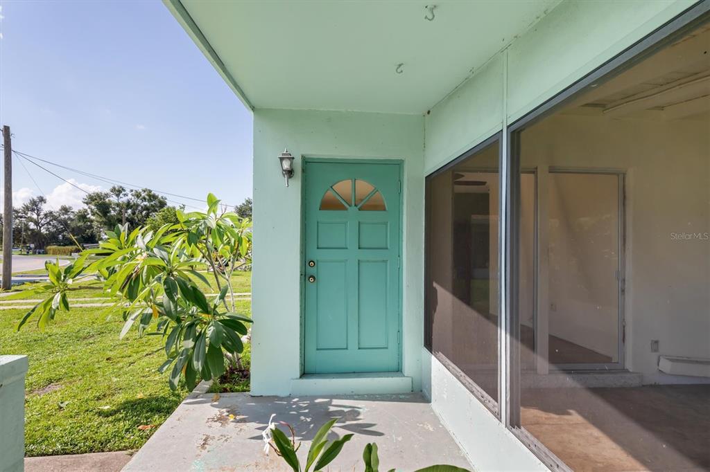 A teal front door sits on a concrete porch next to a large screened window — 3107 EASY STREET, PORT CHARLOTTE, FL