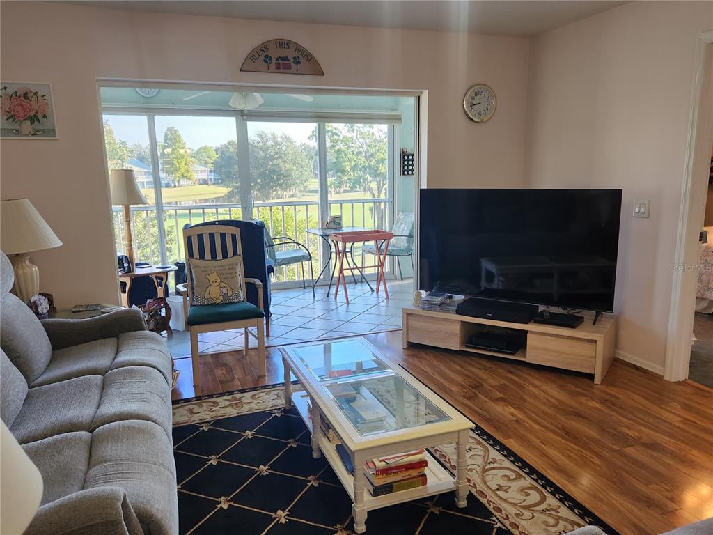 A living room features a glass coffee table, a television, and a balcony with outdoor seating — 6505 STONE RIVER ROAD UNIT 304, BRADENTON, FL