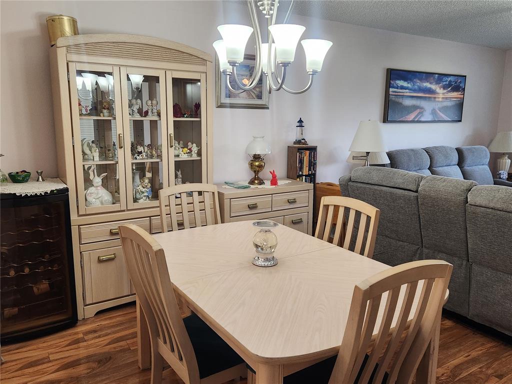 A dining area features a light wood table, matching chairs, a hutch, and a chandelier — 6505 STONE RIVER ROAD UNIT 304, BRADENTON, FL