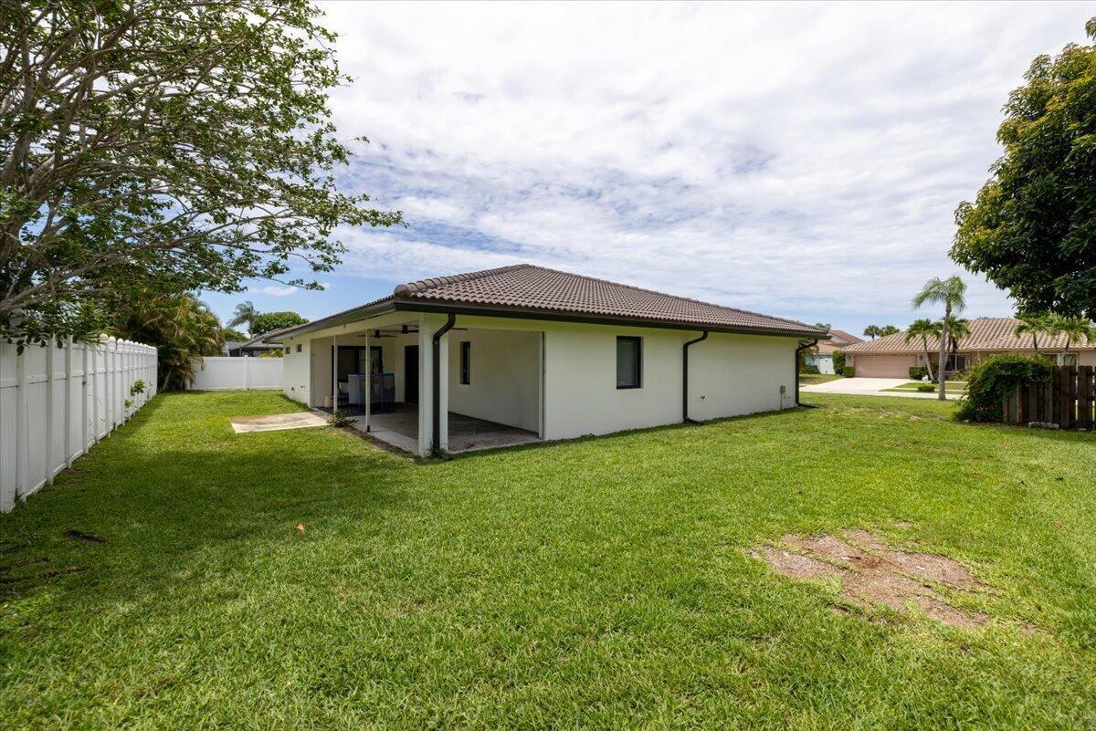 The backyard of a single-story house features a covered patio and a white fence — 6897 Terra Tranquila Drive, Boca Raton FL 33433, BOCA RATON, FL