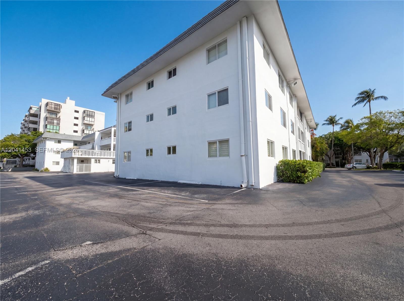 A multi-story white apartment building stands next to an asphalt parking lot — 200 Galen Dr # 202, Key Biscayne FL 33149, KEY BISCAYNE, FL