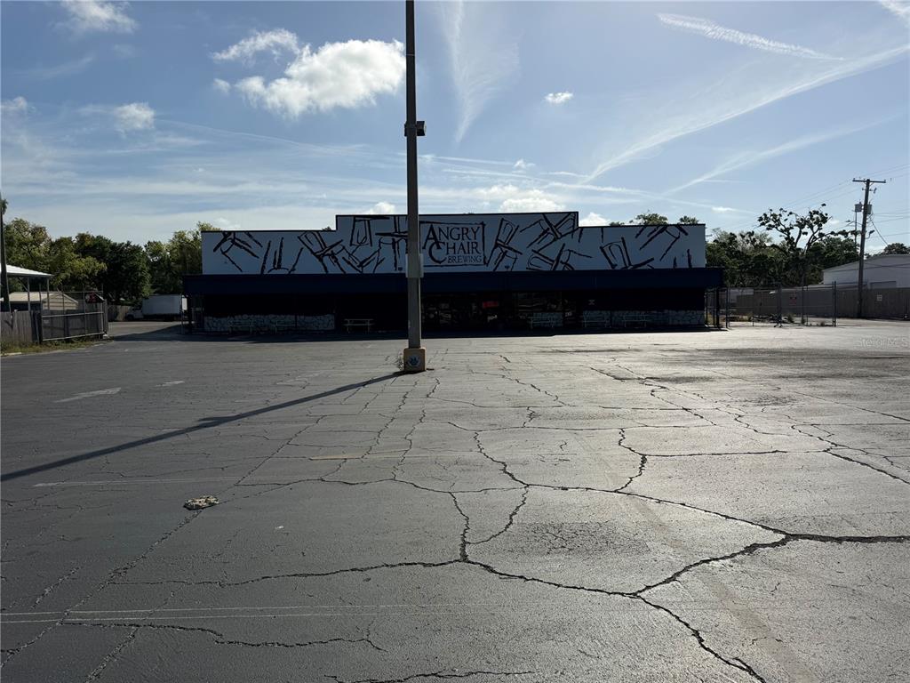 A wide-angle exterior view of a commercial building with a large, cracked asphalt parking lot — 4101 N FLORIDA AVENUE, TAMPA, FL