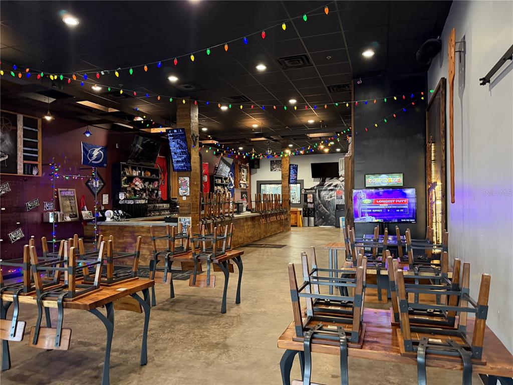 An interior view of a bar with tables stacked with chairs and string lights overhead — 4101 N FLORIDA AVENUE, TAMPA, FL