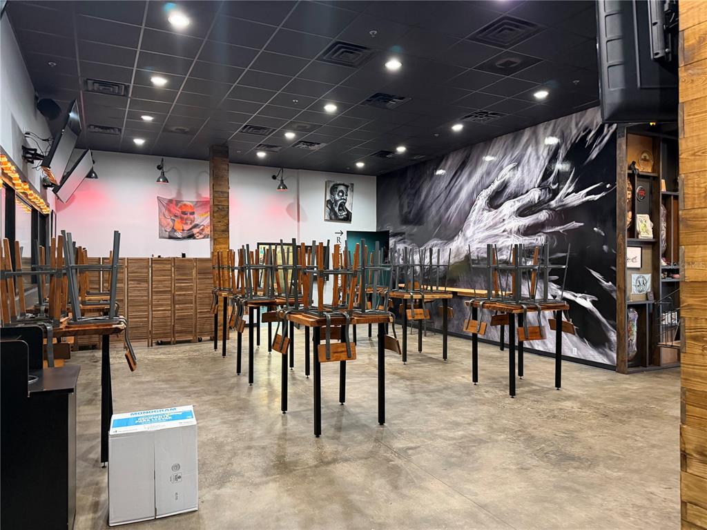 A restaurant dining room features tables with chairs stacked on top and a large mural — 4101 N FLORIDA AVENUE, TAMPA, FL