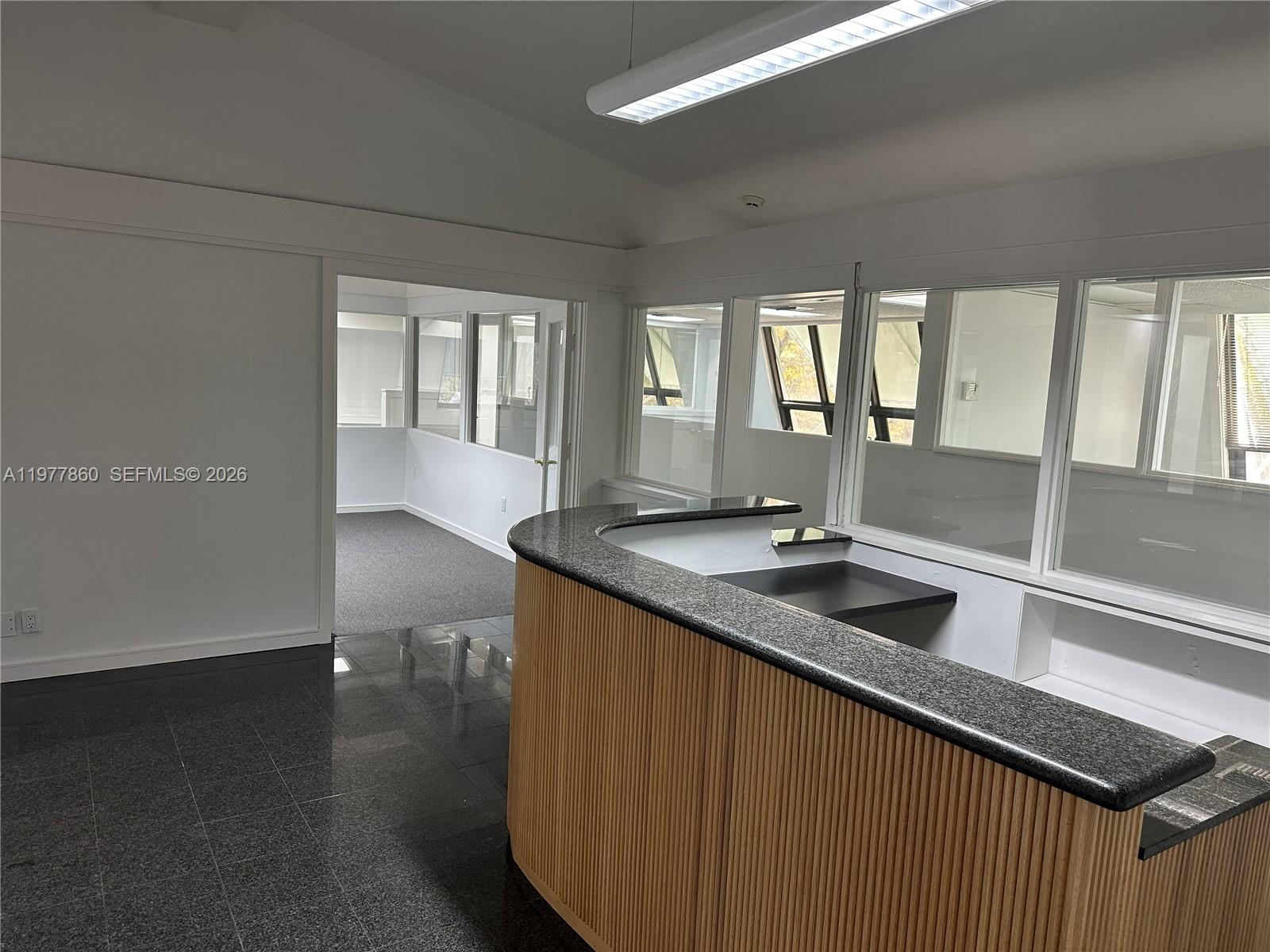 An office interior features a curved reception desk with a granite countertop and tiled flooring — 7910 SW 57th Ave # 23, South Miami FL 33143, SOUTH MIAMI, FL