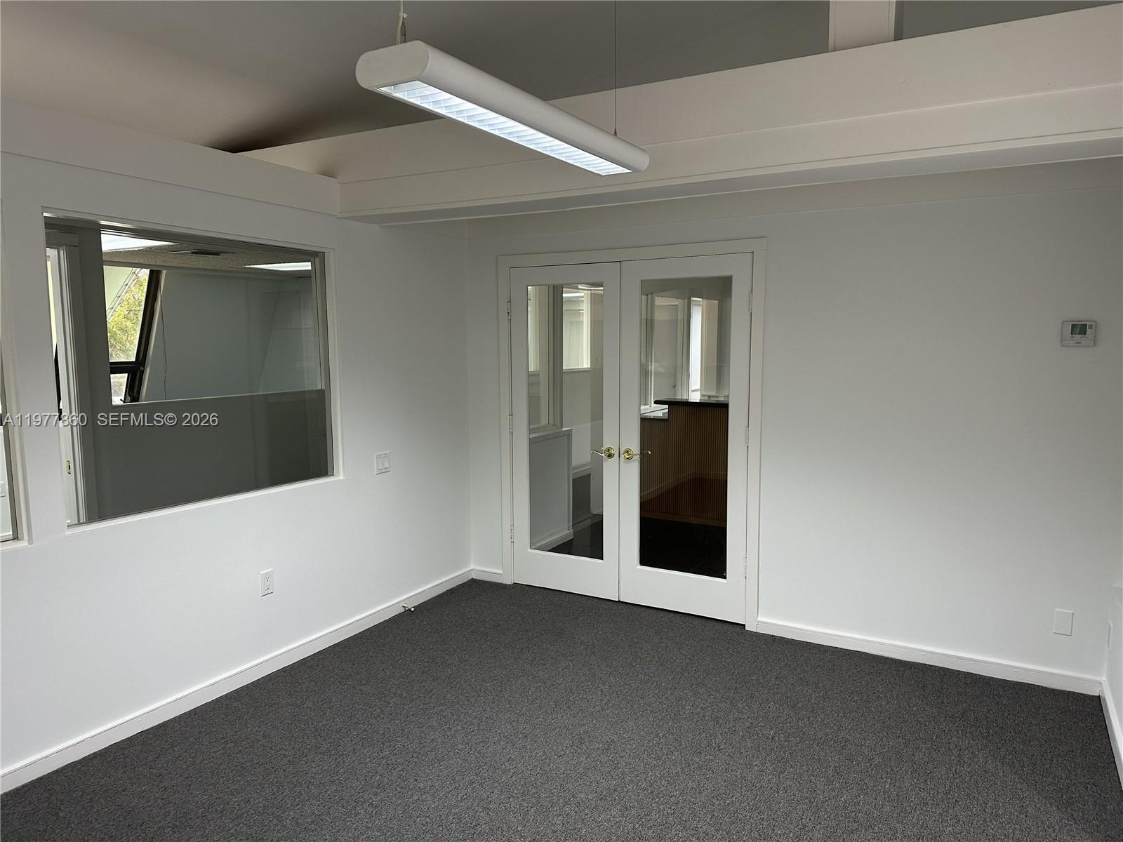 This office space features gray carpeting, white walls, a glass-paneled door, and a rectangular light — 7910 SW 57th Ave # 23, South Miami FL 33143, SOUTH MIAMI, FL