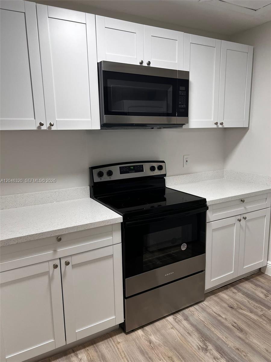 A kitchen features white shaker cabinets, stainless steel appliances, and light-colored speckled countertops — HIALEAH, FL