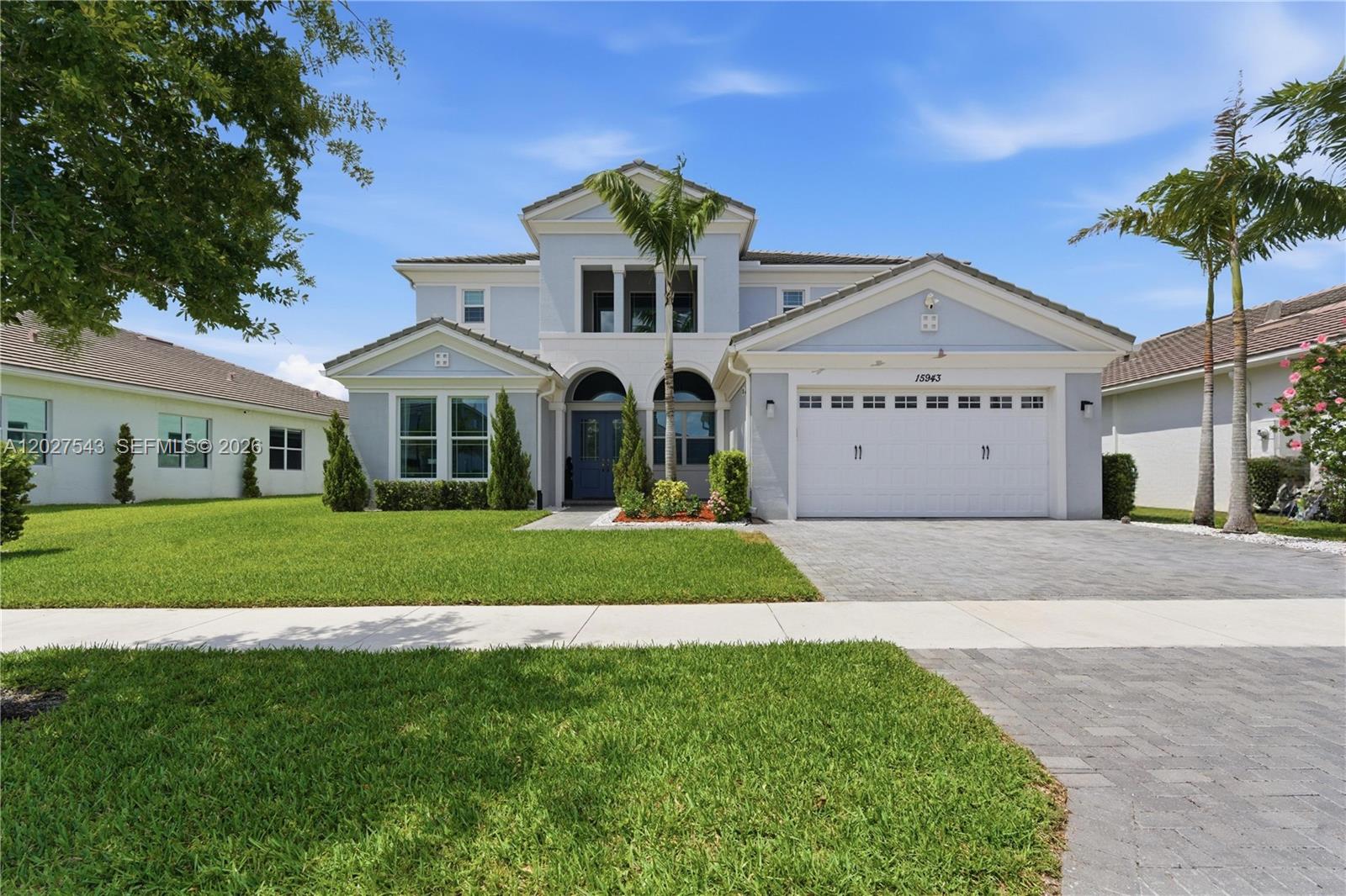 A two-story light blue house with a white garage and a palm tree in front — 15943 Whippoorwill CIR, Westlake FL 33470, WESTLAKE, FL