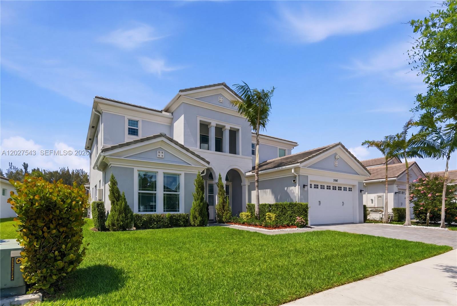 A two-story light gray house with a white garage and a manicured front lawn — 15943 Whippoorwill CIR, Westlake FL 33470, WESTLAKE, FL