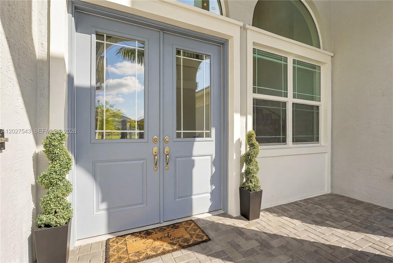 A light blue double front door with glass panels sits on a paved porch — 15943 Whippoorwill CIR, Westlake FL 33470, WESTLAKE, FL