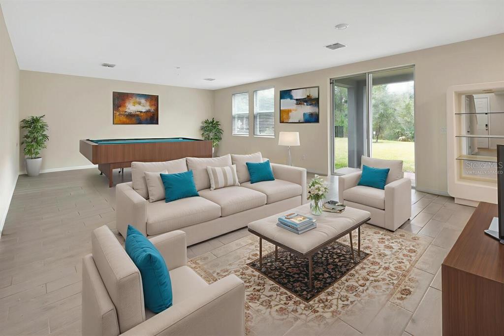 A living room with a pool table, beige furniture, tile floors, and a sliding glass door — 335 NW SARAH NICOLE WAY, NEW SMYRNA BEACH, FL