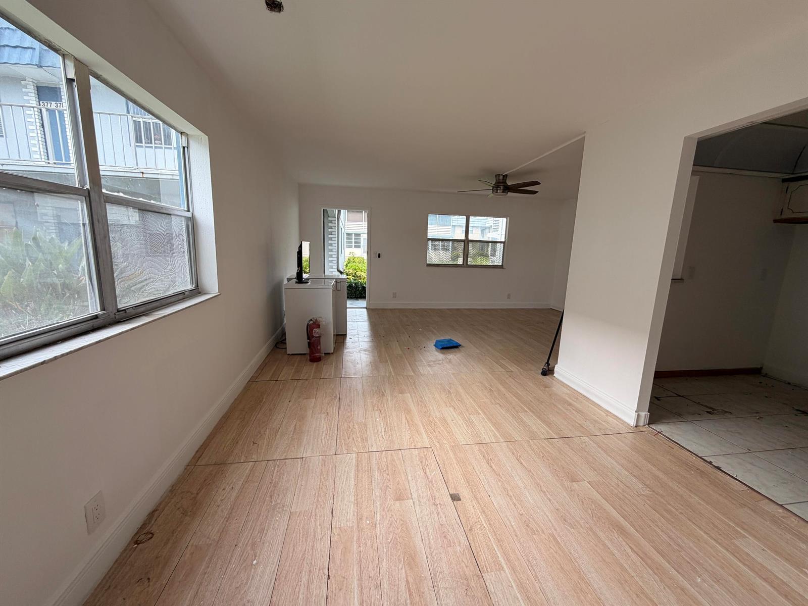 An empty living area features light wood-look flooring, white walls, and a ceiling fan — 355 Brittany H, Delray Beach FL 33446, DELRAY BEACH, FL