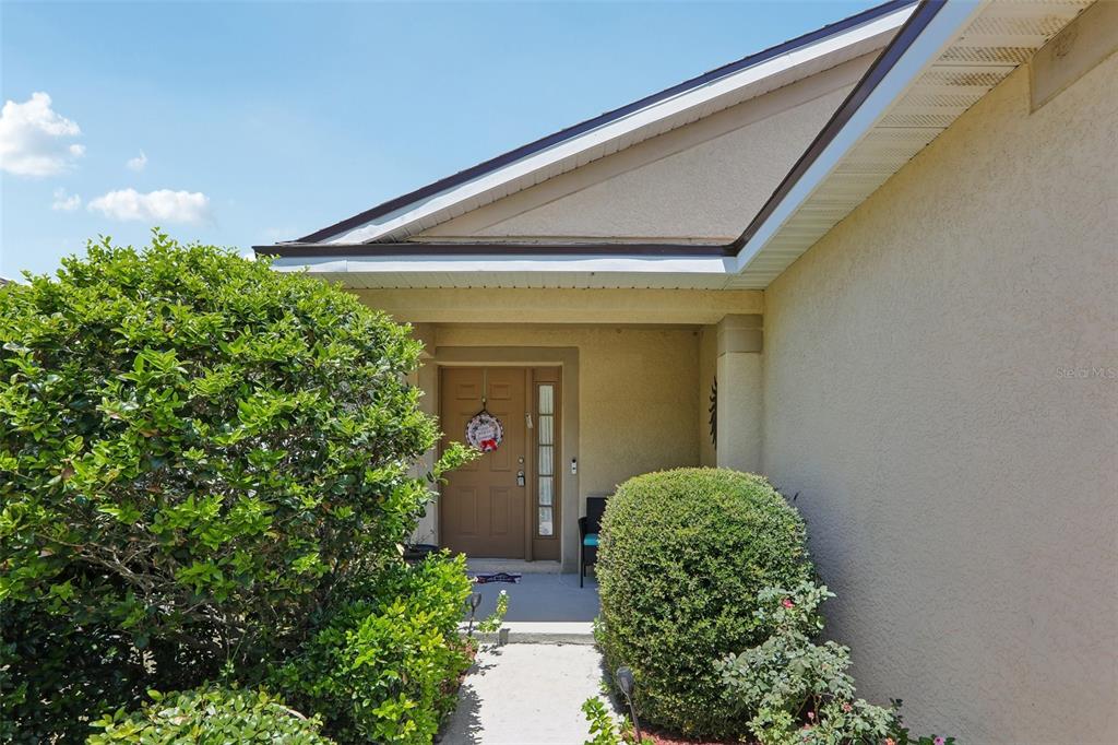 A concrete walkway leads to the front entrance of a house with beige stucco siding — 11339 PALM ISLAND AVENUE, RIVERVIEW, FL