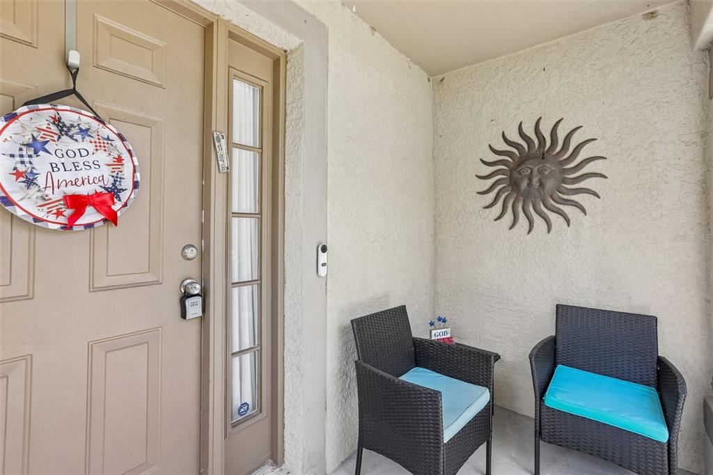 A covered entryway features a tan door, two wicker chairs, and a sun wall decoration — 11339 PALM ISLAND AVENUE, RIVERVIEW, FL