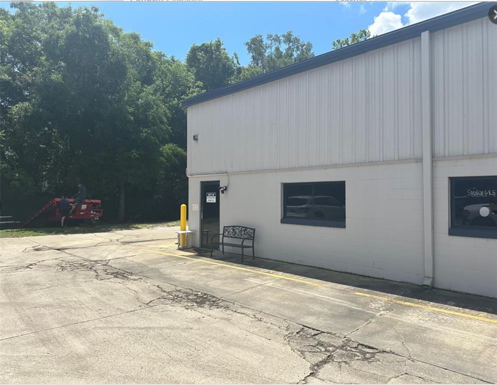 A side view of a commercial building with a concrete parking lot and a bench — 2920 W AIRPORT BOULEVARD UNIT 150, SANFORD, FL