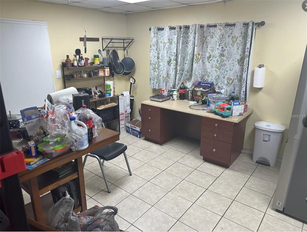 A kitchen area features a desk, a wooden table, tile flooring, and a wall-mounted rack — 2920 W AIRPORT BOULEVARD UNIT 150, SANFORD, FL