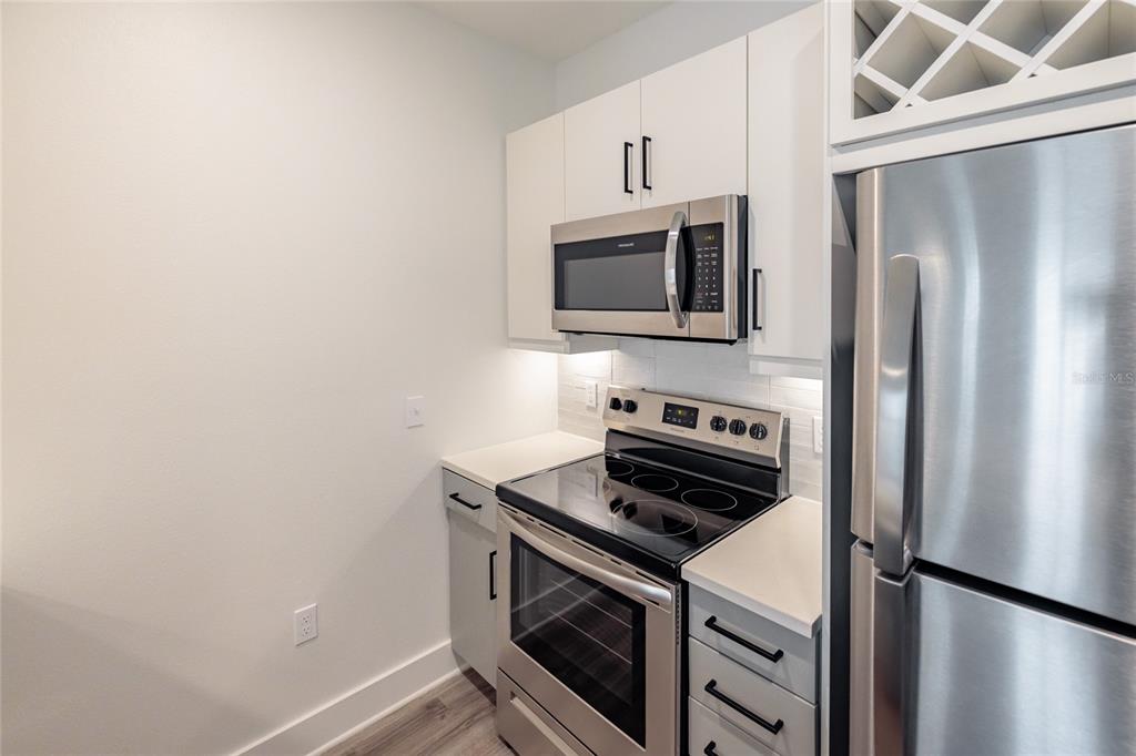 A kitchen features stainless steel appliances, white cabinets, and light-colored countertops — 1420 LAKEFRONT DRIVE UNIT 4305, SARASOTA, FL