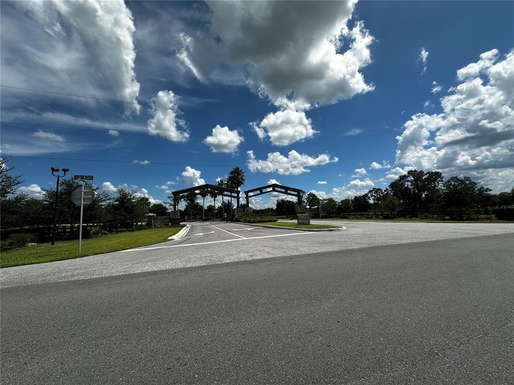 An asphalt road leads to a gated entrance with wooden structures under a cloudy sky — 16950 CR 630 UNIT 123, LAKE WALES, FL