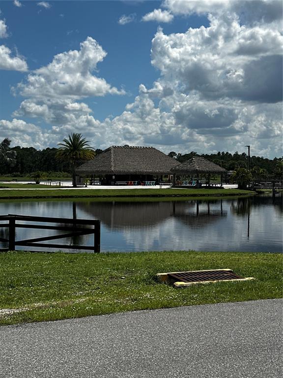 A thatched-roof pavilion sits beside a pond with a wooden fence in the foreground — 16950 CR 630 UNIT 123, LAKE WALES, FL