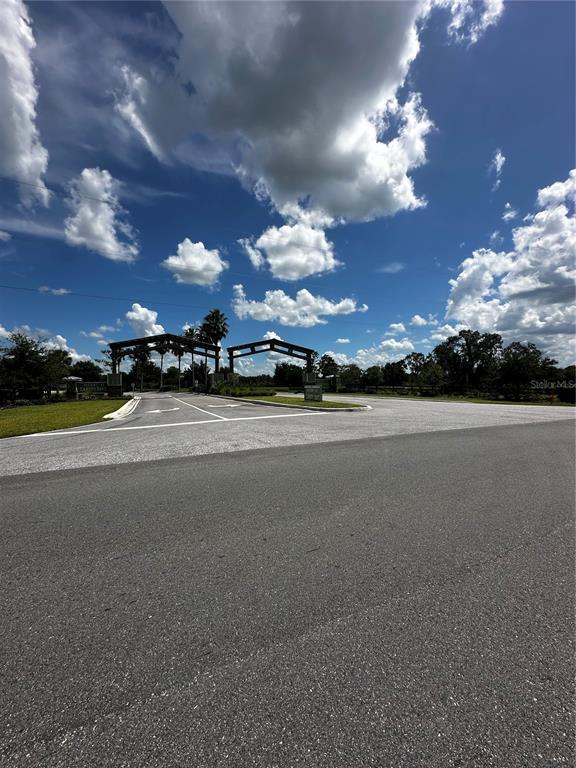A paved road leads to a gated entrance with wooden structures under a blue sky — 16950 CR 630 UNIT 123, LAKE WALES, FL