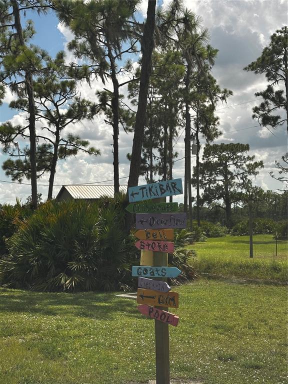 A wooden signpost with multiple directional arrows points toward various resort amenities in a grassy field — 16950 CR 630 UNIT 123, LAKE WALES, FL