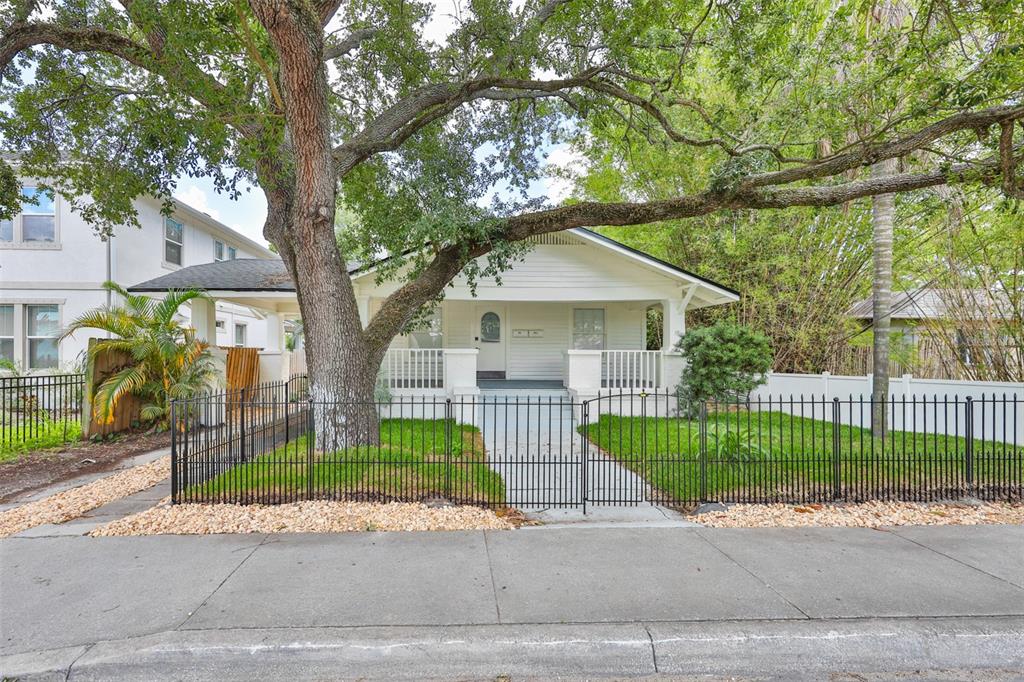 A covered porch features white siding, a blue tiled floor, outdoor furniture, and potted plants — 902 W COLUMBUS DRIVE, TAMPA, FL