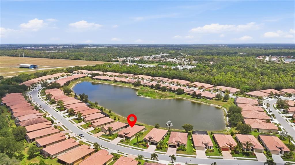 An aerial view shows a residential neighborhood with houses surrounding a central lake — 20252 PEZZANA DRIVE, VENICE, FL