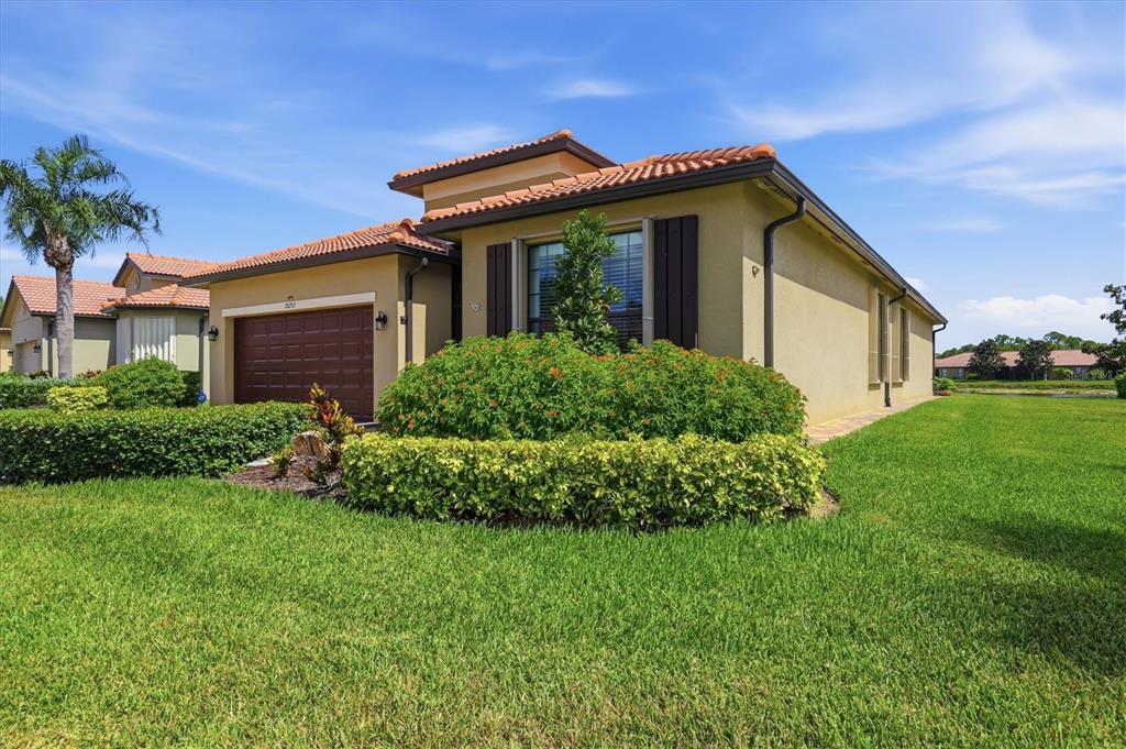 A single-story house with a tan stucco exterior, tile roof, and a two-car garage — 20252 PEZZANA DRIVE, VENICE, FL