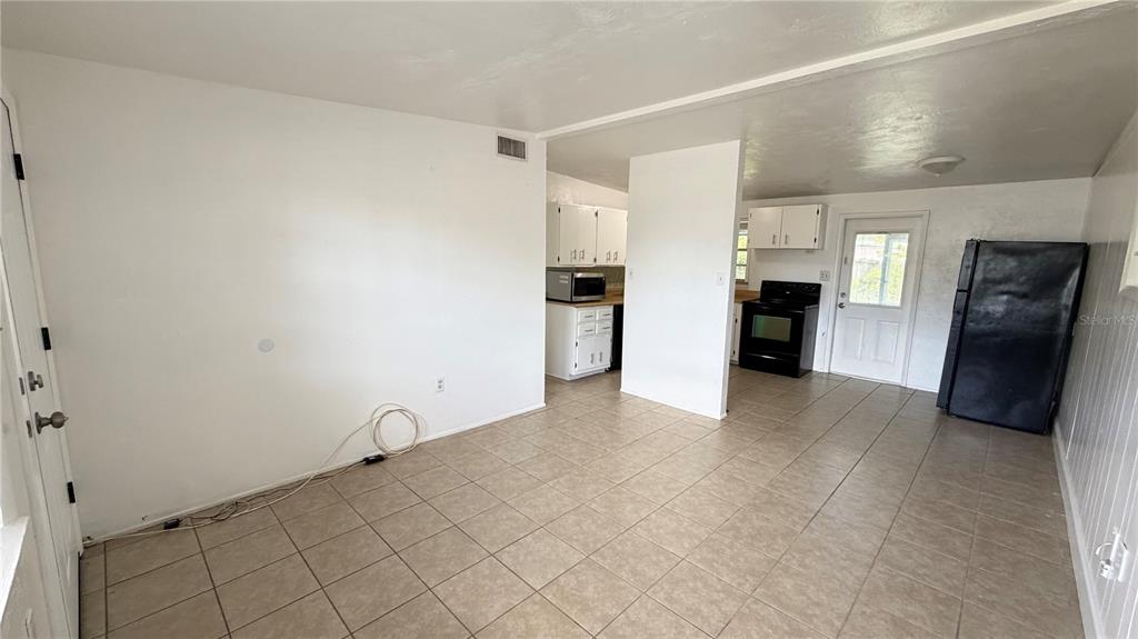 An open kitchen and dining area features white cabinets, tile flooring, and a black refrigerator — 8574 94TH AVENUE, SEMINOLE, FL