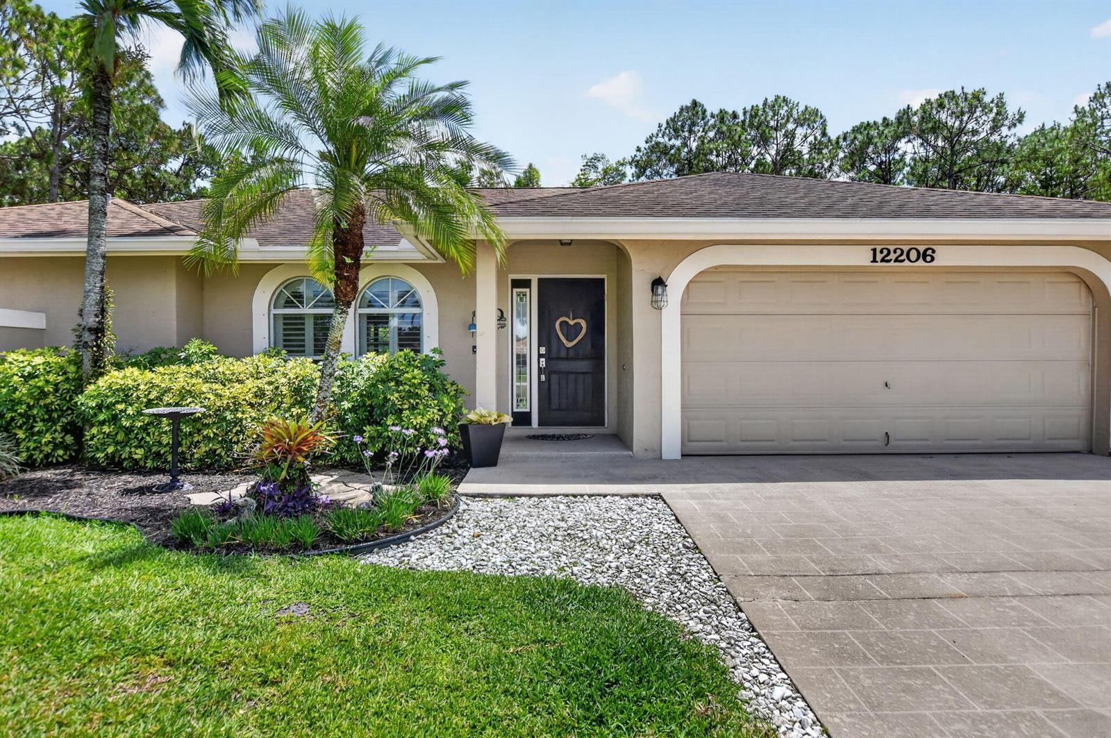 A single-story house features a tan stucco exterior, a two-car garage, and a palm tree — 12206 Temple Boulevard, FL 33412, FL
