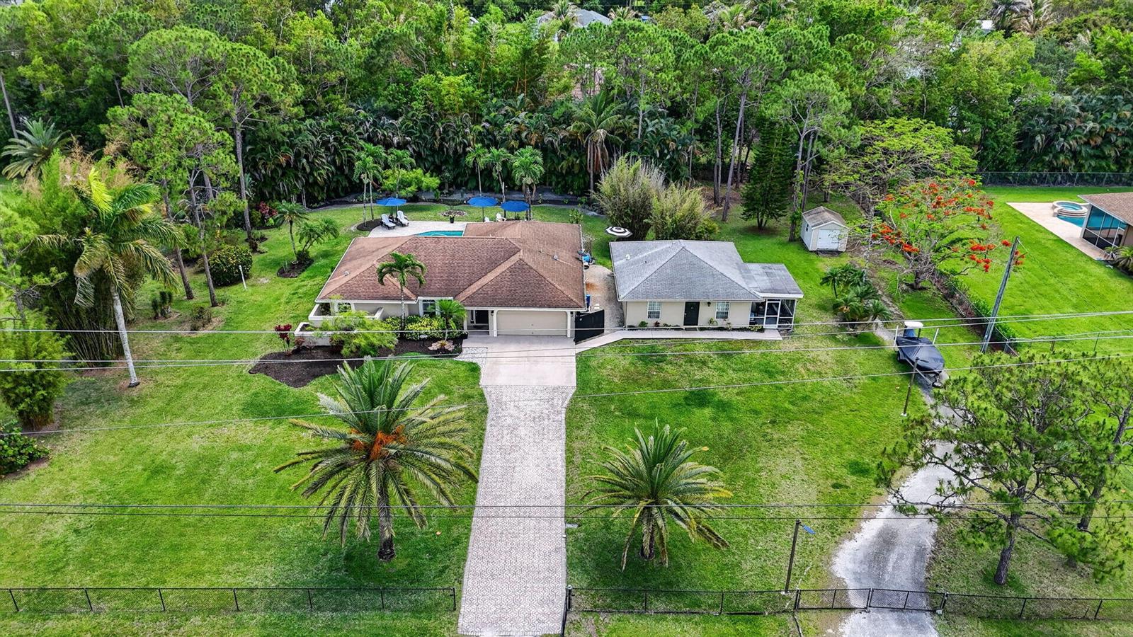 An aerial view shows two houses with brown and gray roofs on a large grassy lot — 12206 Temple Boulevard, FL 33412, FL