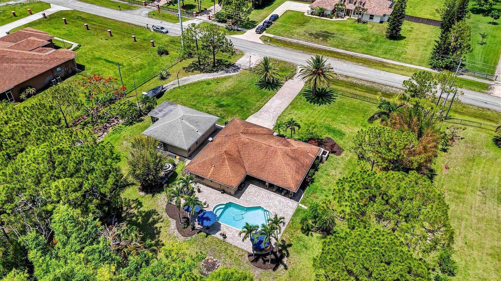An aerial view shows a house with a brown roof, swimming pool, and detached garage — 12206 Temple Boulevard, FL 33412, FL