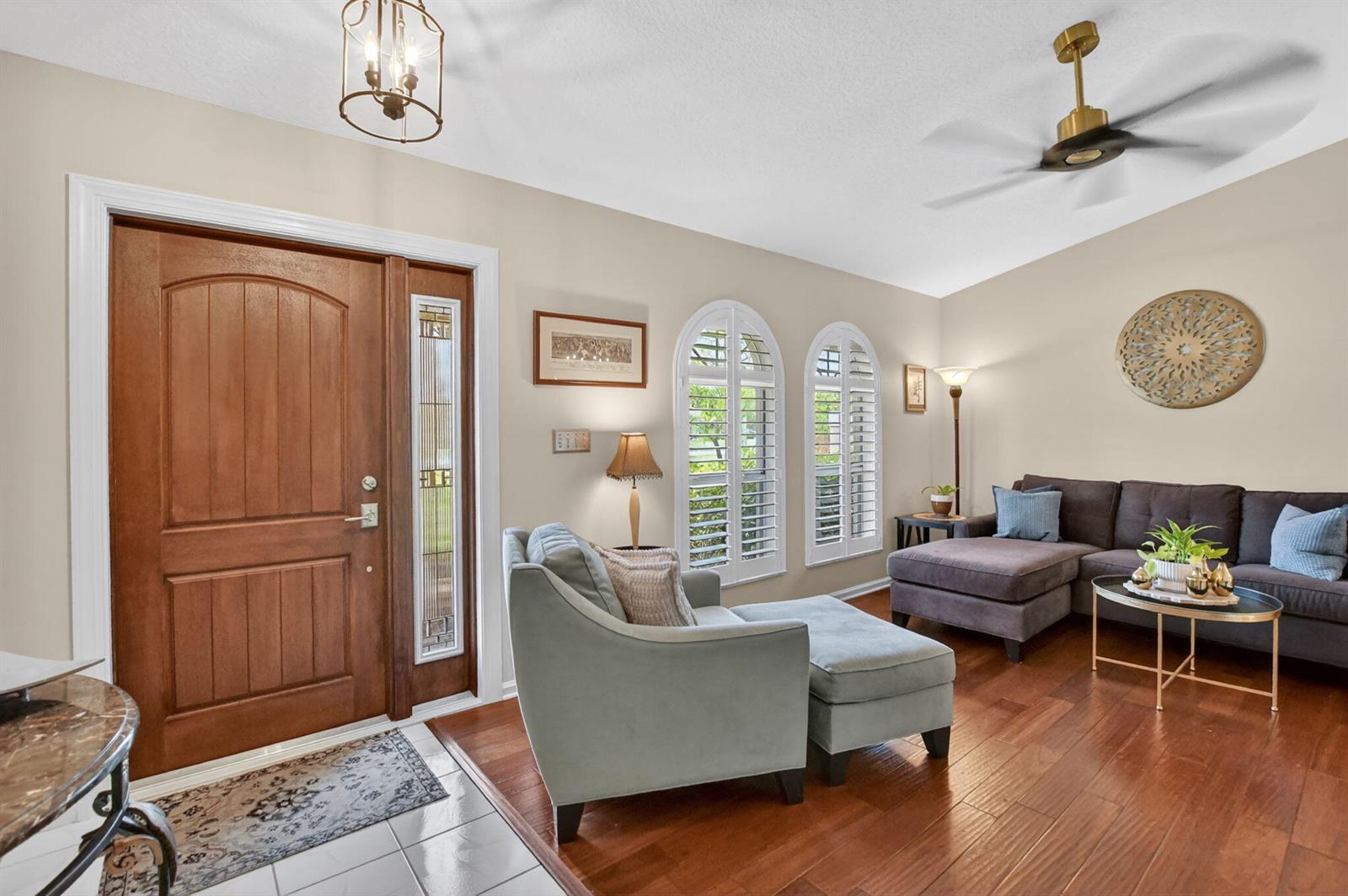 A living room features hardwood floors, a sectional sofa, an armchair, and arched windows — 12206 Temple Boulevard, FL 33412, FL