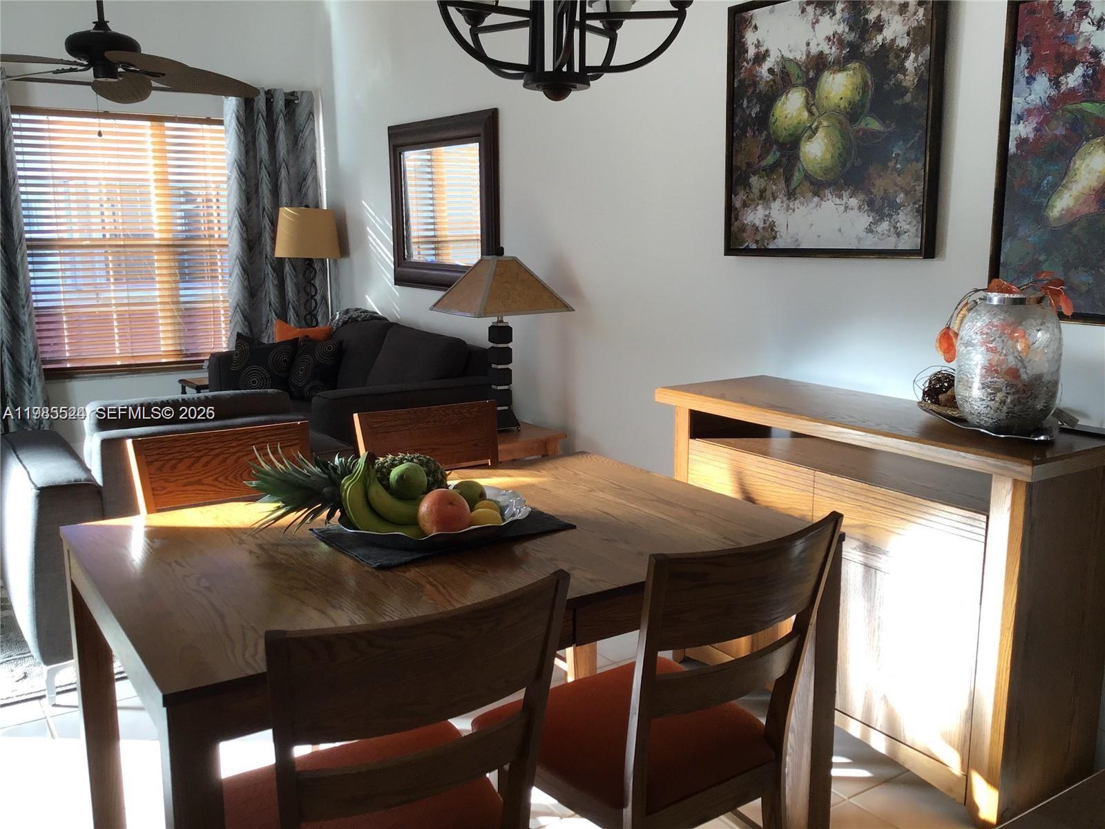 A dining area features a wooden table with fruit, chairs, and a matching sideboard — 609 Waterside Dr # 609, Hypoluxo FL 33462, HYPOLUXO, FL